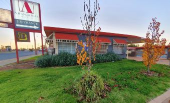 a red roof building with a sign and a tree in front of it , under an overcast sky at Ardeanal Motel