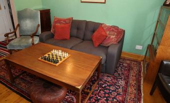 a cozy living room with a couch , coffee table , and chess board on top of a wooden dining table at Acorns Guest House