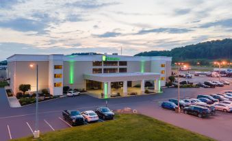 an exterior view of a hotel with a parking lot in front , surrounded by green grass at Holiday Inn Morgantown - Reading Area