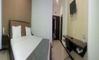 a hotel room with a bed , desk , and tv , as well as a bathroom with a toilet at Jazz Hotel Palu