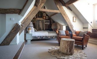 a cozy bedroom with a sloped ceiling , wooden beams , and a bed , along with a cozy living room area at The Frogmill Hotel