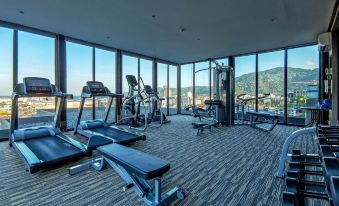 This modern-style home features a gym with large windows that offer a view of the city, as well as various fitness equipment at Dinso Resort & Villas Phuket, Vignette Collection