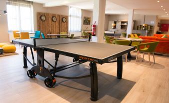 a ping pong table is set up in a room with chairs and a clock on the wall at Hotel Acropolis