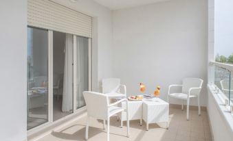 a white room with a dining table , chairs , and a sliding glass door leading to a balcony at Nautilus