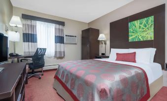 a large bed with a gray and red comforter is in the middle of a room with a window at Ramada by Wyndham Minneapolis Golden Valley