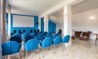 a large room with blue chairs arranged in rows and a projector screen on the wall at Hotel Minerva