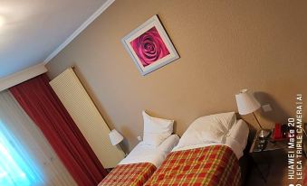 a bed with a plaid blanket and white pillows is in a room with red curtains at La Cote d'Or