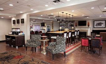 a modern hotel lobby with wooden floors , white walls , and various furniture including armchairs and couches at Hampton Inn Moultrie
