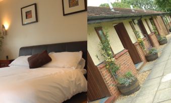a bedroom with a bed and pillows , and a building with a small window , both decorated with plants at The Carrington Arms