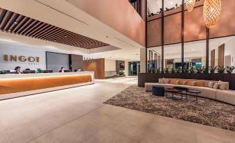 a modern hotel lobby with a large reception desk , multiple couches , and a dining area at Ingot Hotel Perth, Ascend Hotel Collection