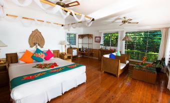 a spacious bedroom with hardwood floors , a large bed , and multiple chairs arranged around the room at Nukubati Great Sea Reef