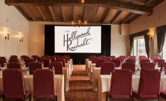 a conference room with rows of red chairs and a large screen at the front at The Hollywood Roosevelt