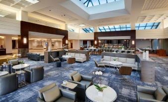 a large , modern hotel lobby with multiple couches and chairs arranged around a dining table at Hyatt Regency Dulles