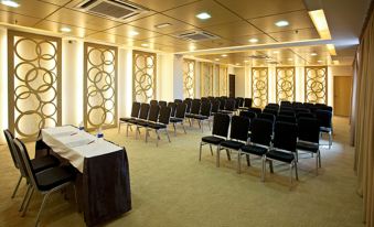 a conference room with rows of chairs arranged in a semicircle , and a podium at the front of the room at Pinetree Hotel