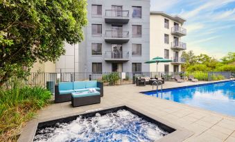 a large swimming pool with a hot tub next to it and an apartment building in the background at Oaks Sydney North Ryde Suites