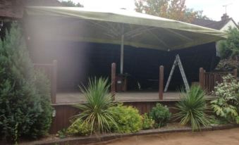 a large outdoor event tent with a stage , set up in a grassy area near trees and bushes at The Eight Bells
