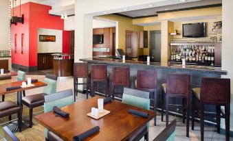 a restaurant with a bar area and dining tables , where people are seated and enjoying their meals at Hilton Garden Inn Albany
