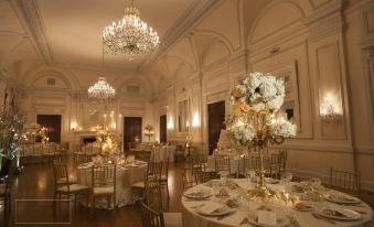 a large , elegant room with multiple tables set for a formal event , adorned with gold and white decorations at Oheka Castle Hotel & Estate