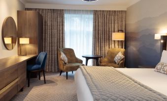 a hotel room with a large bed , two chairs , a desk , and a window with curtains at Mercure Blackburn Dunkenhalgh Hotel & Spa