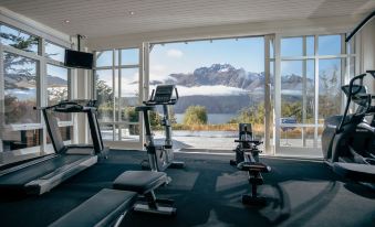 a gym with large windows overlooking a mountain range and a body pump area in front at Rosewood Matakauri
