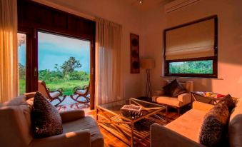 a living room with a couch , chairs , and coffee table is shown with a view of the outside at The Serai Bandipur