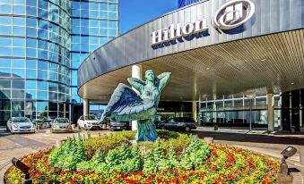 a large building with a statue in front of it and the hilton sign on the ground at Hilton Dallas Lincoln Centre