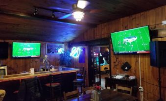 a bar with two large flat screen tvs displaying a soccer game , surrounded by wooden walls at RiverBend Lodge