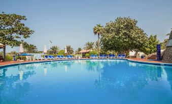 a large outdoor swimming pool surrounded by palm trees , with several lounge chairs placed around the pool for relaxation at Marbella Resort