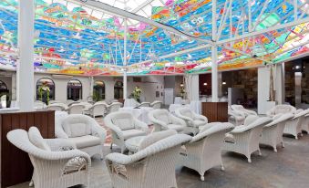 a room with white wicker chairs and tables , a colorful ceiling decoration , and plants at Hotel Olympia Valencia