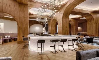 a modern bar with a marble counter and black stools , surrounded by wooden columns and a large chandelier at Signia by Hilton San Jose