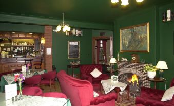 a cozy living room with green walls , red chairs , and a fireplace , creating a warm and inviting atmosphere at Atholl Arms