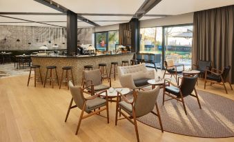 a modern coffee shop with wooden floors , chairs , and tables , as well as a bar area at Briig Boutique Hotel