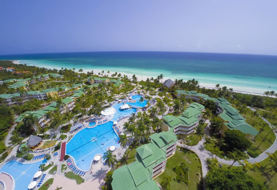 aerial view of a resort with a large pool surrounded by palm trees and beach chairs at Tryp Cayo Coco