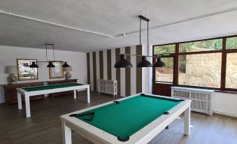 a room with two pool tables , one on the left and one on the right , surrounded by chairs at Parador de Gredos