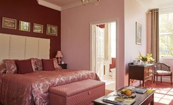 a large bed with a pink comforter is in the middle of a room with red walls at Corse Lawn House Hotel