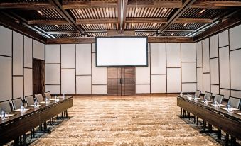 a large conference room with a wooden floor , a projector screen , and several chairs arranged for a meeting at Nobu Hotel Los Cabos