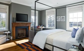 a modern bedroom with a black canopy bed , white bedding , and a flat - screen tv on the wall at Topping Rose House