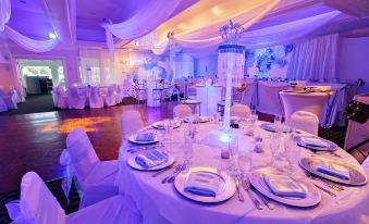 a well - decorated banquet hall with multiple tables set up for a formal event , each table is adorned with white tablecloths and silver at Grand Palms Spa & Golf Resort