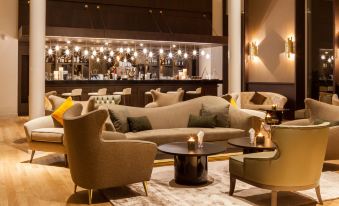 a modern lounge area with several couches and chairs , creating a comfortable and inviting atmosphere at AC Hotel Paris le Bourget Airport