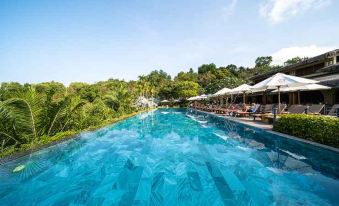 a large outdoor swimming pool surrounded by lounge chairs and umbrellas , providing a relaxing atmosphere for guests at Lahana Resort Phu Quoc & Spa