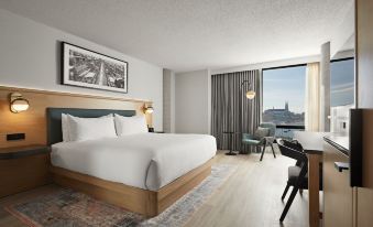 a large bed with white linens is in a hotel room with a view of the city at Hotel Moco Valleyfield