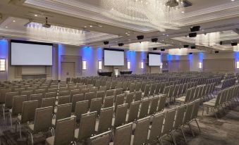 a large , well - lit conference room with rows of chairs arranged in front of a stage at Courtyard Oshawa