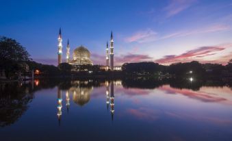 a large mosque with a tall dome and two minarets is reflected in the water at Hotel Lavender Senawang