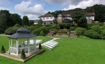 a wedding ceremony taking place in a lush green field , with rows of white chairs set up for guests at Burnley West Higher Trapp Hotel