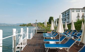 a wooden deck overlooking the water , with several lounge chairs and umbrellas placed along the edge at Hotel Eden