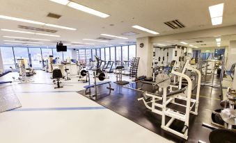 a well - equipped gym with various exercise equipment , including treadmills and weight machines , in a spacious room at Century Plaza Hotel