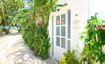 "a white building with a sign that says "" lucky "" is surrounded by green bushes and trees" at Keyla Inn