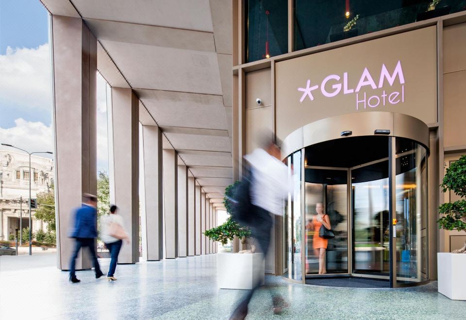 "a modern building entrance with a sign for "" glam hotel "" and people walking in front" at Glam Milano