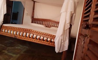 a wooden bed with a canopy is covered in white fabric , and the room is dark wood at Blue Rooms