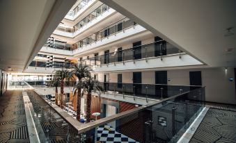 a modern atrium with multiple floors , balconies , and black and white checkered flooring , surrounded by palm trees at Sunprime C-Lounge